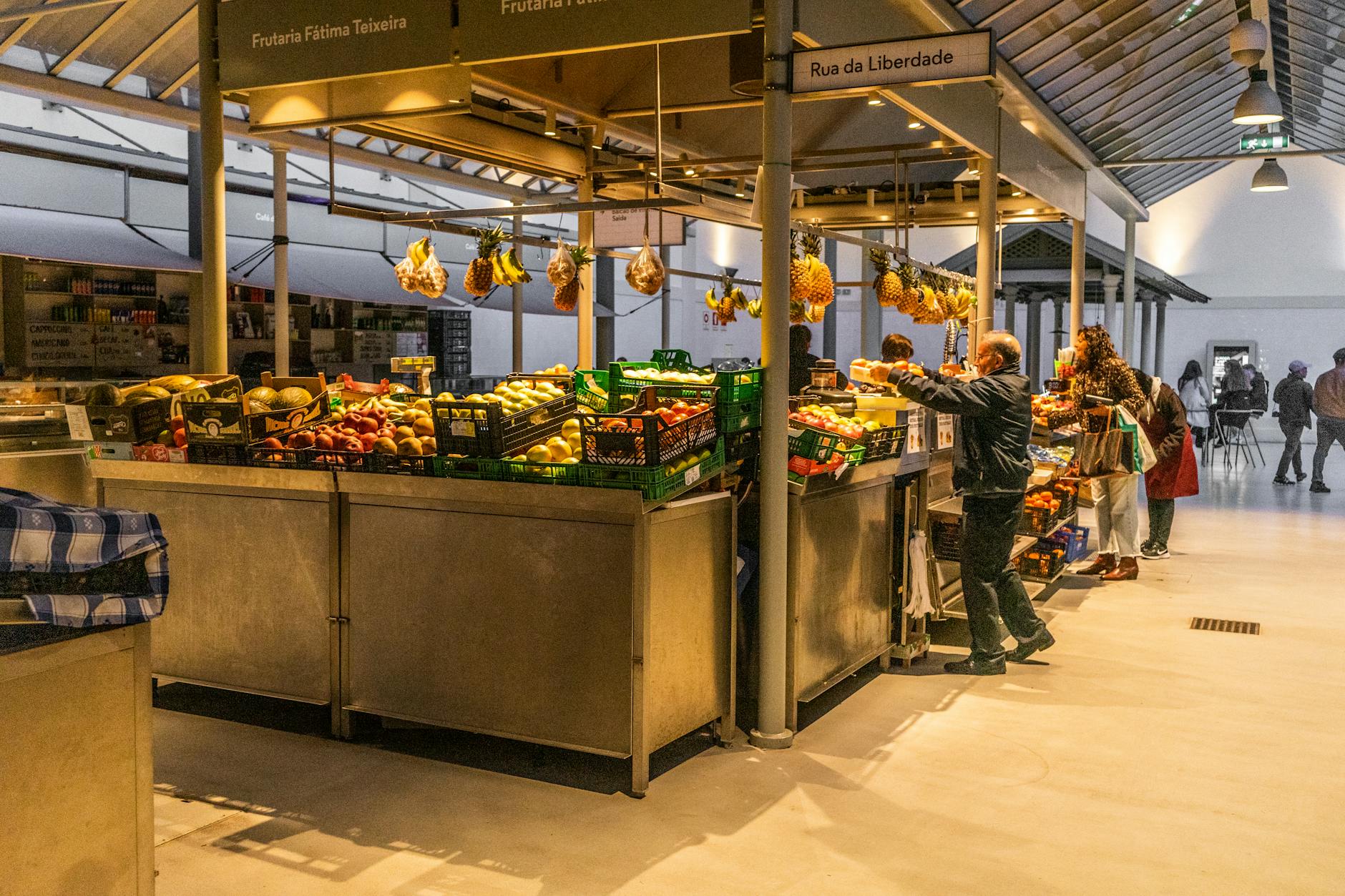 people shopping at market stands with fruits in portugal
